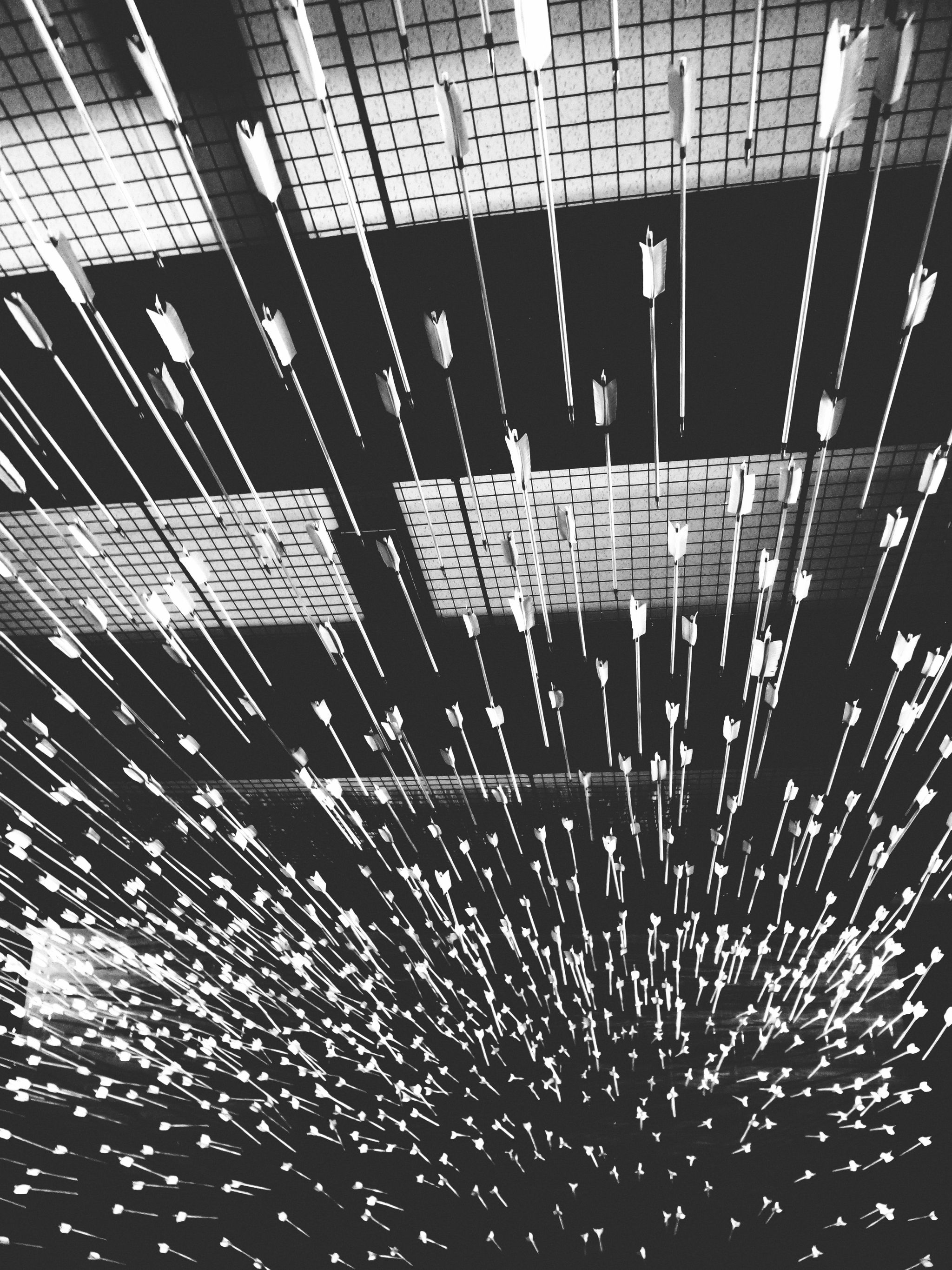Image noir et blanche de plusieurs flèches qui se dirigent vers le même point